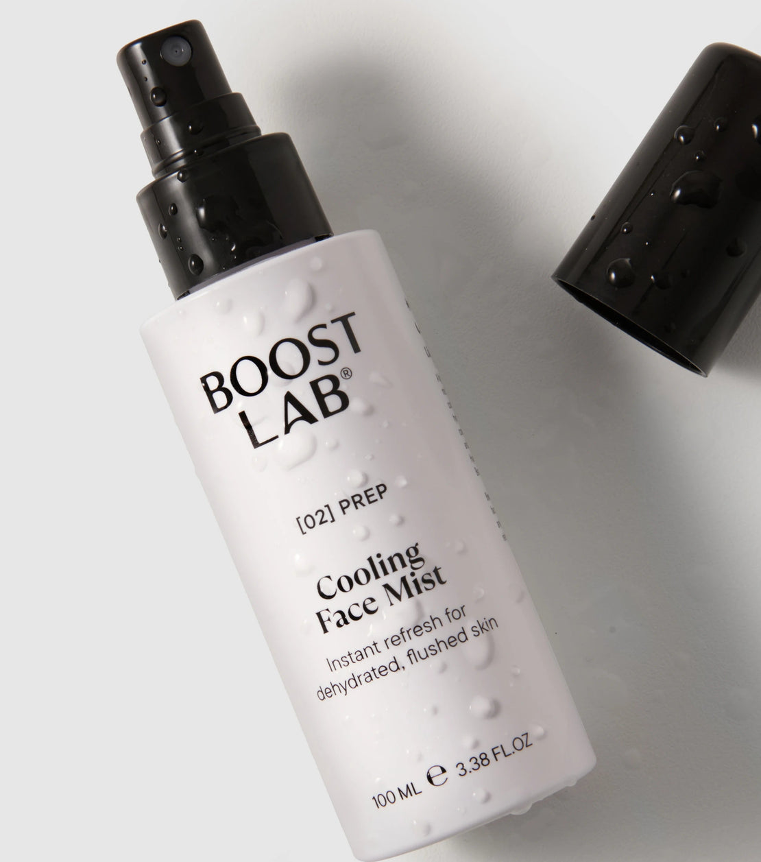 A 100 mL bottle of BOOST LAB Cooling Face Mist with a black spray nozzle, shown on a light gray background with its black cap placed beside it.