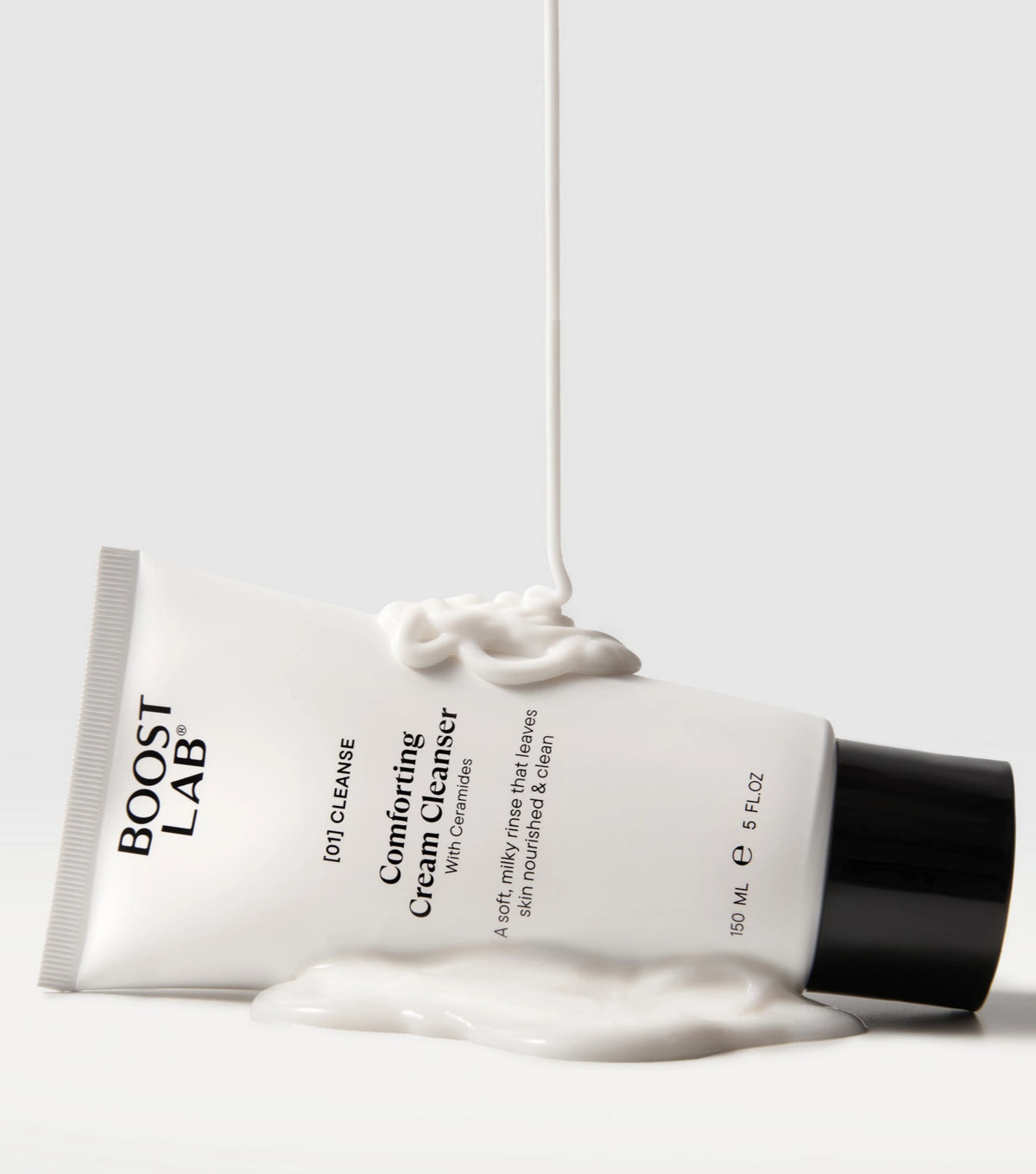 Boost Lab Comforting Cream Cleanser tube lying on its side with cream cleanser drizzling onto it
