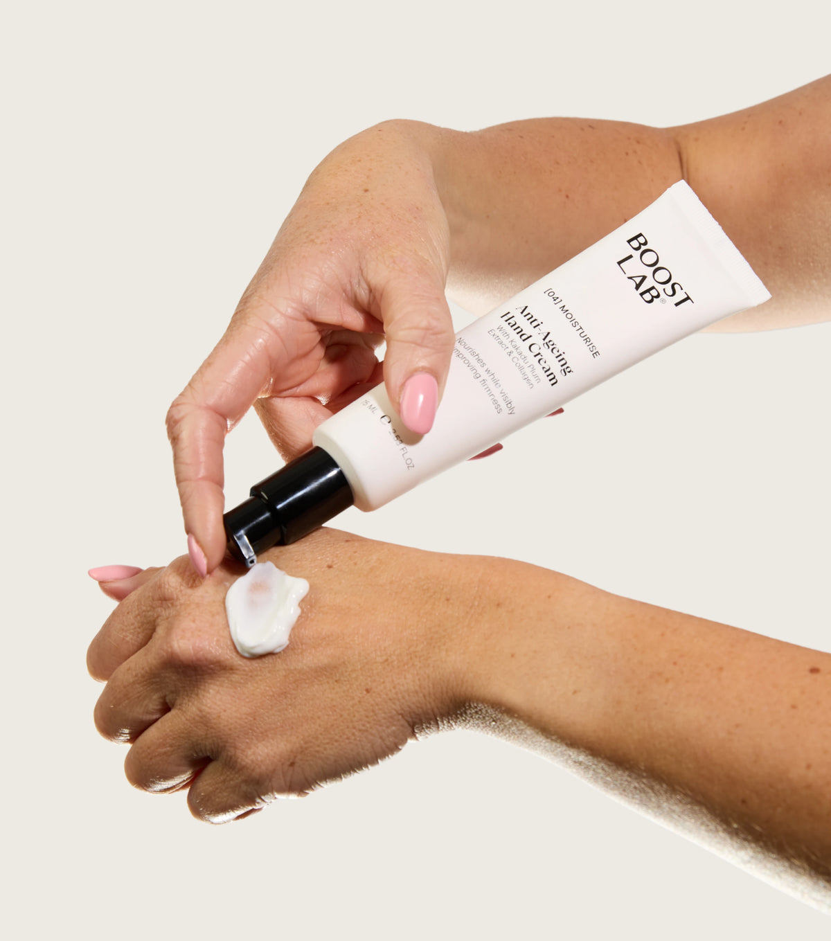 Hand squeezing Boost Lab Anti-Ageing Hand Cream onto the back of the other hand